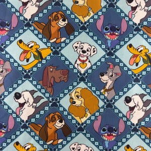 Puede incluir: Una tela estampada con perros de dibujos animados en un diseño repetitivo. Los perros están dentro de formas de diamante azules, con un fondo azul claro. Los perros incluyen un dálmata, Pluto y Stitch.