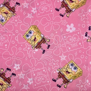 May include: Pink fabric with a repeating pattern of SpongeBob SquarePants, starfish, flowers, and other shapes. The SpongeBob characters are yellow with brown trousers and black shoes. The background is a solid pink colour.