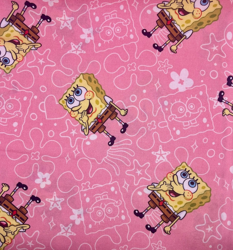 May include: Pink fabric with a repeating pattern of SpongeBob SquarePants, starfish, flowers, and other shapes. The SpongeBob characters are yellow with brown trousers and black shoes. The background is a solid pink colour.