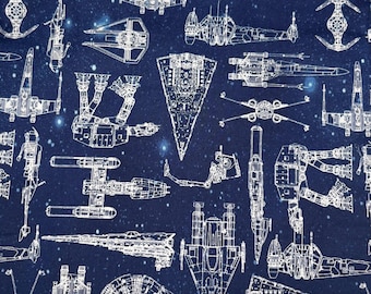 Puede incluir: Tela azul marino con un patrón repetitivo de dibujos lineales blancos de varias naves espaciales y vehículos espaciales. El diseño incluye planos detallados de naves espaciales, sobre un fondo de diminutas estrellas blancas.