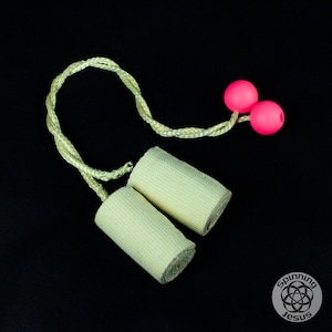 May include: Off-white fire poi with pink spheres and a braided cord. The cylindrical poi heads are made of a textured fabric. The background is black, and the logo "Spinning Jesus" is in the lower right corner.