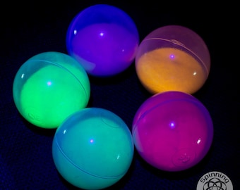 May include: Six glow-in-the-dark balls in different colors: green, purple, yellow, blue, teal, and pink. The balls are arranged in a circle on a black background.