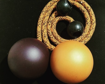 May include: Two brown juggling balls and two black juggling balls with a yellow and black rope. The balls are made of a smooth, shiny material.