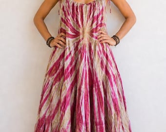 Puede incluir: Un vestido largo sin mangas con un vibrante estampado tie-dye en tonos magenta y beige. La prenda presenta un escote redondo fruncido, tirantes finos ajustables con lazos y una falda escalonada con una silueta fluida y amplia.