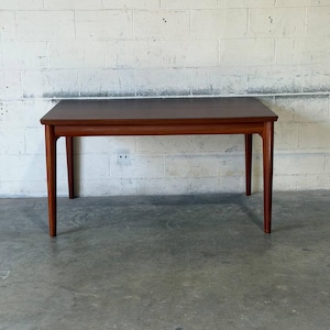 May include: A rectangular wooden dining table with a smooth, dark brown top and four tapered legs. The table features a clean, simple design with a horizontal apron connecting the legs, showcasing a consistent wood grain finish throughout the piece.