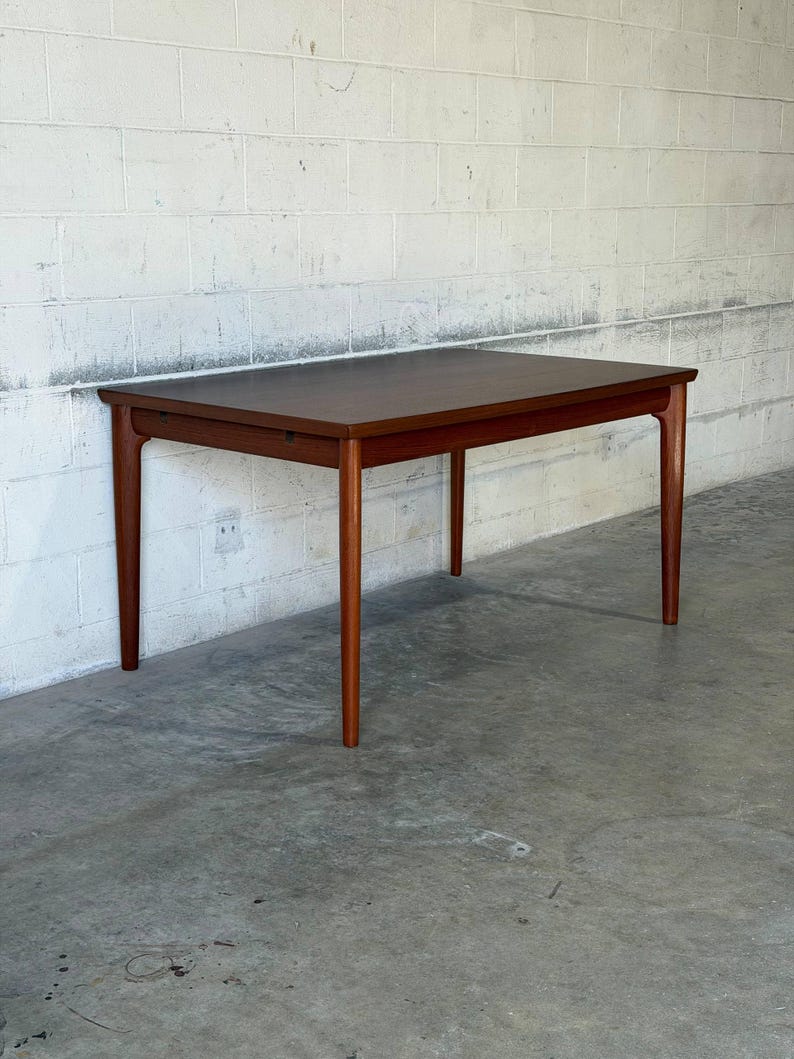 May include: A rectangular wooden dining table with a smooth, dark brown finish. The table features four tapered legs that extend from the corners, supporting a flat, solid top with clean, straight edges and a visible wood grain texture throughout.
