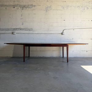 May include: A rectangular dark wood dining table featuring a smooth, flat tabletop surface and four tapered legs. The table has a clean, horizontal profile with a visible wood grain texture and a deep brown finish, standing on a level floor.