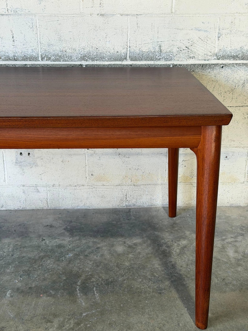 May include: A rectangular wooden table with a dark brown top and a lighter brown frame. The table features four tapered legs that extend from the corners, showcasing a smooth, polished finish and visible wood grain throughout the entire structure.