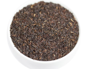 May include: A white bowl filled with loose leaf black tea.
