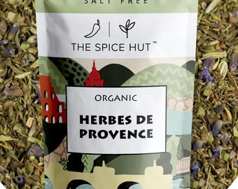 May include: A light green pouch of The Spice Hut organic Herbes de Provence seasoning. The label features a landscape illustration, the text Flavors of Europe, Salt Free, and a net weight of 1 oz / 28 g. The pouch is filled with dried green herbs.