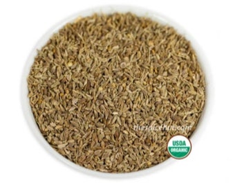 May include: A white bowl filled with dried anise seeds. The seeds are a light brown color and have a slightly rough texture. The bowl is sitting on a white background. The text "thespicehut.com" is visible on the bottom right of the image. A green USDA Organic label is visible on the bottom right of the image.