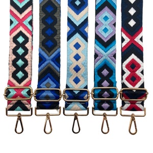 May include: Five colorful patterned straps with gold metal clasps. The straps are made of woven fabric and feature geometric designs in shades of blue, pink, white, and black.