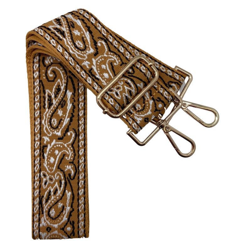 Puede incluir: Una correa ajustable con un patr&oacute;n de paisley marr&oacute;n y blanco y herrajes de metal dorado. La correa tiene dos cierres giratorios.