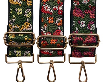 Pode incluir: Três tiras de tecido com padrão floral colorido com fechos de metal dourado e ganchos giratórios. As tiras são verdes com flores rosa, amarelas e laranja.
