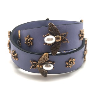 May include: A purple leather belt with gold bee and flower embellishments. The bees have pearl accents.