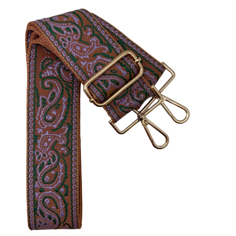 Puede incluir: Una correa ajustable con un patr&oacute;n paisley marr&oacute;n y morado y herrajes de metal dorado. La correa es adecuada para bolsos o carteras.