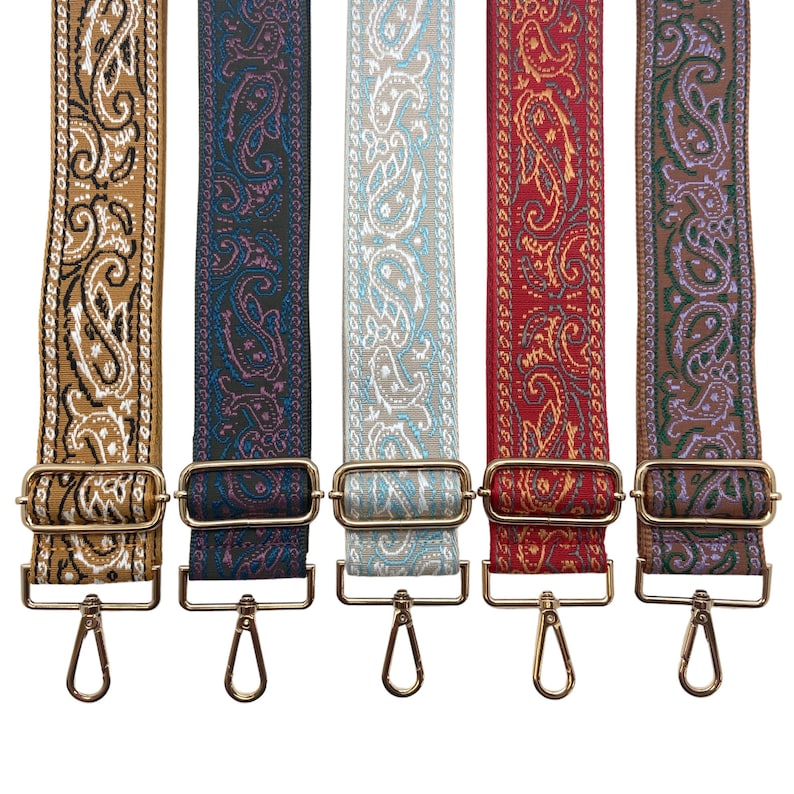 Puede incluir: Cinco correas de tela con diferentes patrones y cierres de metal dorado. Las correas son marr&oacute;n, azul oscuro, azul claro, rojo y marr&oacute;n con detalles morados.