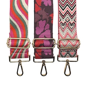 Puede incluir: Tres correas de bolso coloridas con herrajes dorados. Las correas presentan diferentes diseños: un diseño de rayas onduladas en rosa, naranja y verde; un estampado floral en morado y rojo; y un estampado de chevrón con corazones en rosa y blanco.