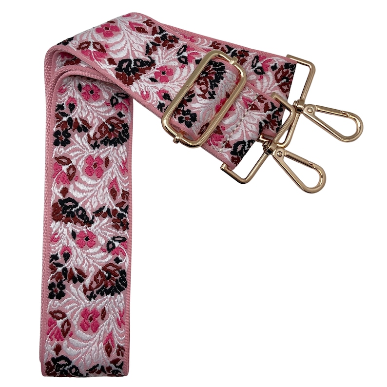 Puede incluir: Una correa ajustable con un patr&oacute;n floral rosa y blanco y herrajes de metal dorado. La correa tiene dos cierres giratorios.
