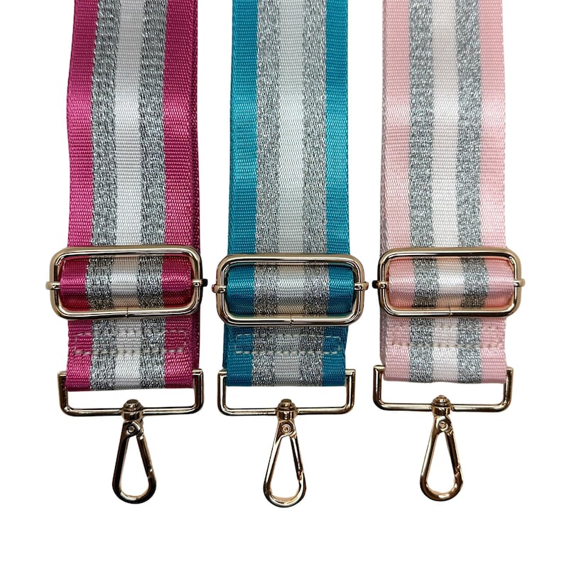 Peut inclure: Trois bandouli&egrave;res r&eacute;glables pour sacs &agrave; main, roses, turquoise et rose clair. Chaque sangle pr&eacute;sente des rayures argent&eacute;es et blanches, une quincaillerie m&eacute;tallique dor&eacute;e et un mousqueton pivotant. Pour sacs &agrave; main.