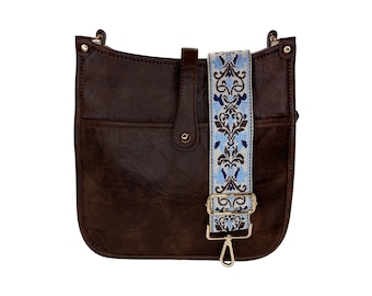 May include: A brown leather crossbody bag with a blue and white patterned strap. The bag has a flap closure and a front pocket.