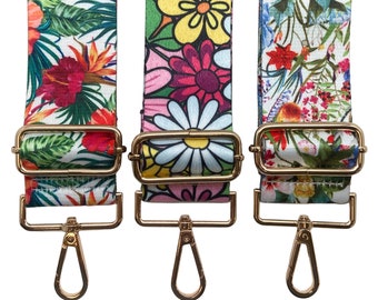 Pode incluir: Três correias ajustáveis com padrão floral colorido e ferragens metálicas douradas. As correias têm um fundo branco com diferentes padrões florais em rosa, vermelho, amarelo, verde e azul.