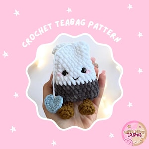 May include: A crocheted teabag pattern in the shape of a smiling teabag with a blue heart tag and brown feet. The teabag is white and gray, with black eyes and pink cheeks. The text "CROCHET TEABAG PATTERN" is above the teabag.