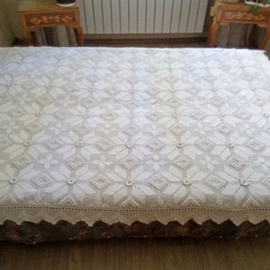 May include: A white crocheted bedspread with a diamond pattern and a scalloped edge.