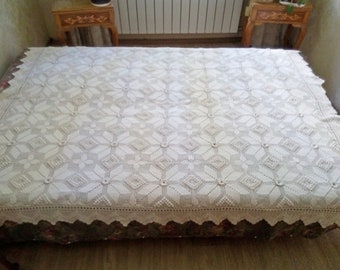 May include: A white crocheted bedspread with a diamond pattern and a scalloped edge.