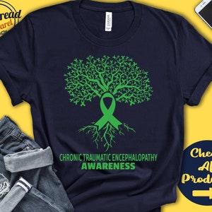 Könnte beinhalten: Ein marineblaues T-Shirt mit einem grünen Baumdesign. Der Baum besteht aus grünen Bändern und hat Wurzeln. Der Text "Chronic Traumatic Encephalopathy Awareness" ist unter dem Baum aufgedruckt.