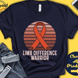 May include: Navy blue t-shirt with a sunset graphic and an orange awareness ribbon. The text "Limb Difference Warrior" is printed on the shirt.