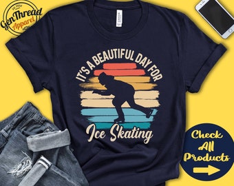 May include: A navy blue t-shirt with a vintage-style graphic of a person ice skating. The graphic has a rainbow color scheme and the text "It's a beautiful day for Ice Skating".