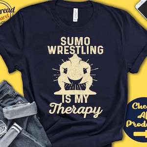May include: Navy blue t-shirt featuring a yellow illustration of a sumo wrestler and the text "Sumo Wrestling is my Therapy".