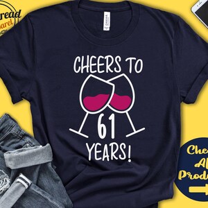 May include: Navy blue t-shirt with white text that reads "Cheers to 61 Years!" and a graphic of two wine glasses with red wine.