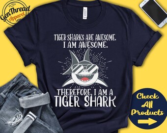 May include: Navy blue t-shirt with a white graphic of a shark wearing sunglasses. The text "Tiger Sharks are Awesome. I am Awesome. Therefore, I am a Tiger Shark" is printed on the shirt.