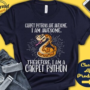 Op de afbeelding: Een marineblauw T-shirt met een witte afbeelding van een cartoon slang met een zonnebril. De tekst op het shirt luidt "Carpet Pythons are awesome. I am awesome. Therefore, I am a Carpet Python."