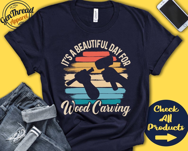 Puede incluir: Una camiseta azul marino con un gr&aacute;fico de estilo vintage que dice "Es un hermoso d&iacute;a para tallar madera". El gr&aacute;fico presenta una puesta de sol con una mano sosteniendo un mazo y un cincel.