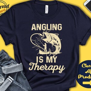 May include: A navy blue t-shirt with a white graphic of a fish being reeled in with the text "Angling is my Therapy".