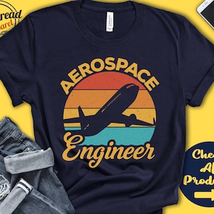 May include: A navy blue t-shirt featuring a vintage-style graphic of an aeroplane flying over a sunset with the text "Aerospace Engineer".