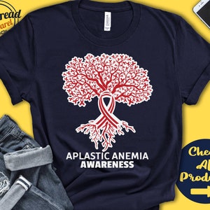 Può includere: Una maglietta blu navy con un design a forma di albero con un nastro rosso e il testo "Aplastic Anemia Awareness".