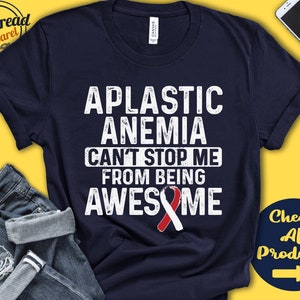 Può includere: Una maglietta blu navy con il testo "Aplastic Anemia Can't Stop Me From Being Awesome" in bianco con un nastro rosso.