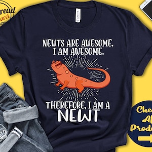 May include: A navy blue t-shirt with a white graphic of a newt wearing sunglasses. The text "Newts are awesome. I am awesome. Therefore, I am a newt" is printed on the shirt.