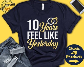 May include: Navy blue t-shirt with white text that reads "10 Years Feel Like Yesterday" and a gold ring with a diamond graphic. The shirt is on a yellow background.