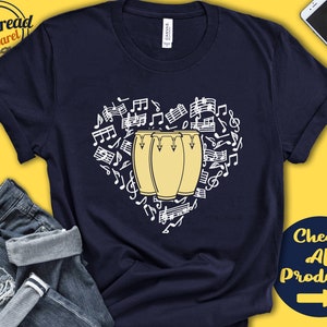 Puede incluir: Camiseta azul marino con un diseño blanco de tres tambores congas amarillos en forma de corazón rodeados de notas musicales. El texto "Check All Products" está en la esquina inferior derecha de la imagen.