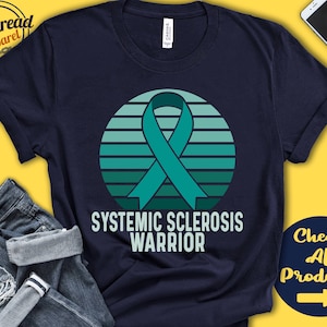 Könnte beinhalten: Ein marineblaues T-Shirt mit einem türkisfarbenen Band und dem Text "Systemic Sclerosis Warrior" in Weiß. Das Band befindet sich auf einem türkisfarbenen, weißen und blauen gestreiften Hintergrund.