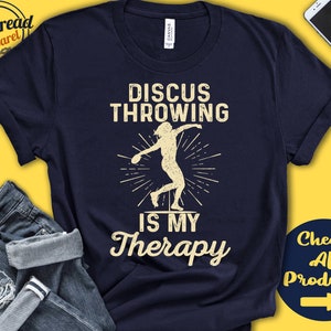 May include: Navy blue t-shirt with a vintage-style graphic of a discus thrower and the text "Discus Throwing is My Therapy".