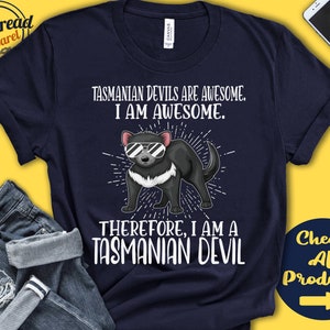 May include: A navy blue t-shirt with a cartoon Tasmanian devil wearing sunglasses. The text on the shirt reads "Tasmanian Devils are awesome. I am awesome. Therefore, I am a Tasmanian Devil."