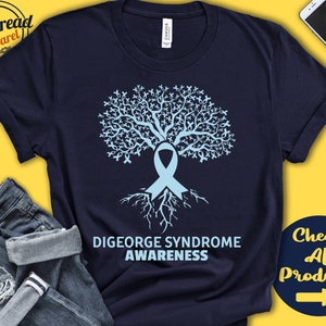 May include: A navy blue t-shirt with a light blue tree design. The tree is made up of ribbon shapes and has a light blue ribbon at the base. The text "DiGeorge Syndrome Awareness" is printed below the tree.