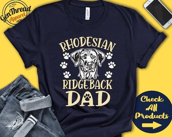 May include: A navy blue t-shirt with the text "Rhodesian Ridgeback Dad" in white and a black and white illustration of a Rhodesian Ridgeback dog's head.