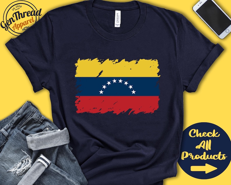 May include: A navy blue t-shirt with a distressed, faded image of the Venezuelan flag. The flag is yellow, blue, and red with a crescent of white stars. The text "Check All Products" is on a blue background with a white arrow pointing to the right.